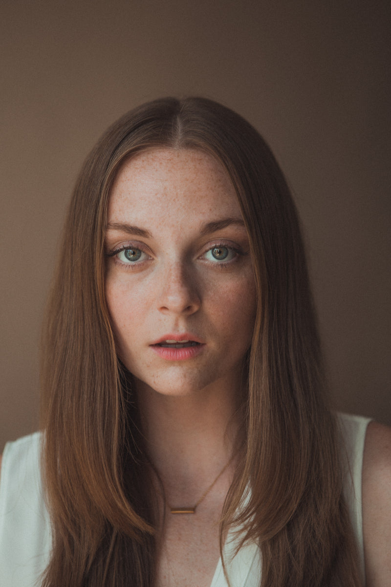 An image of a young woman with fair skin and green eyes