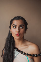 A young woman with radiant skin and long dark hair making a kiss face