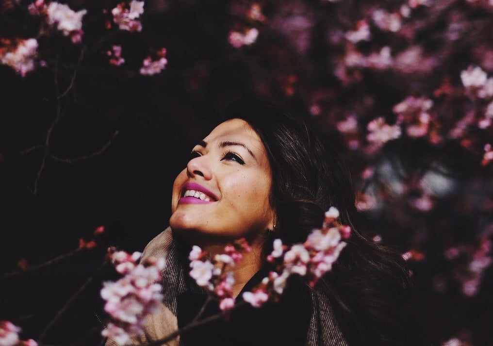 Sara Shah surrounded by flowers gazing up to the sky with a smile